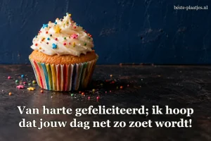 Een cupcake met kleurrijke strooisels staat tegen een donkerblauwe muur.