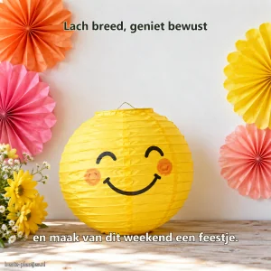 Een handgemaakte gele lampion met glimlach staat tussen kleurrijke papieren rozetten.