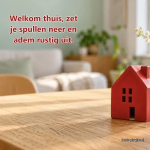 Een klein rood keramisch huisje staat op een lichte eettafel.