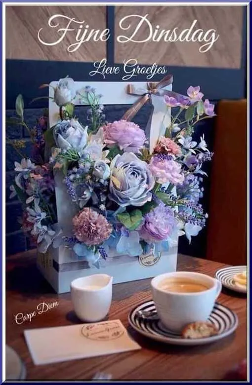 Een bloeiende bloemenarrangement met een kopje koffie en een koekje op een tafel.