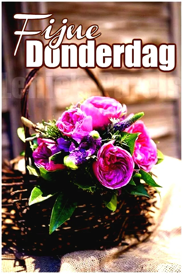 Een mand met roze bloemen op een houten achtergrond. Tekst: Fijne Donderdag.
